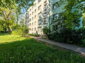 Un edificio residencial de varios pisos con un sendero pavimentado y vegetación.