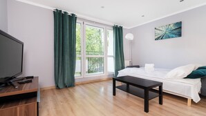 Ein modernes Hotelzimmer mit Bett, Fernseher, Schreibtisch und einem Fenster mit Vorhängen.