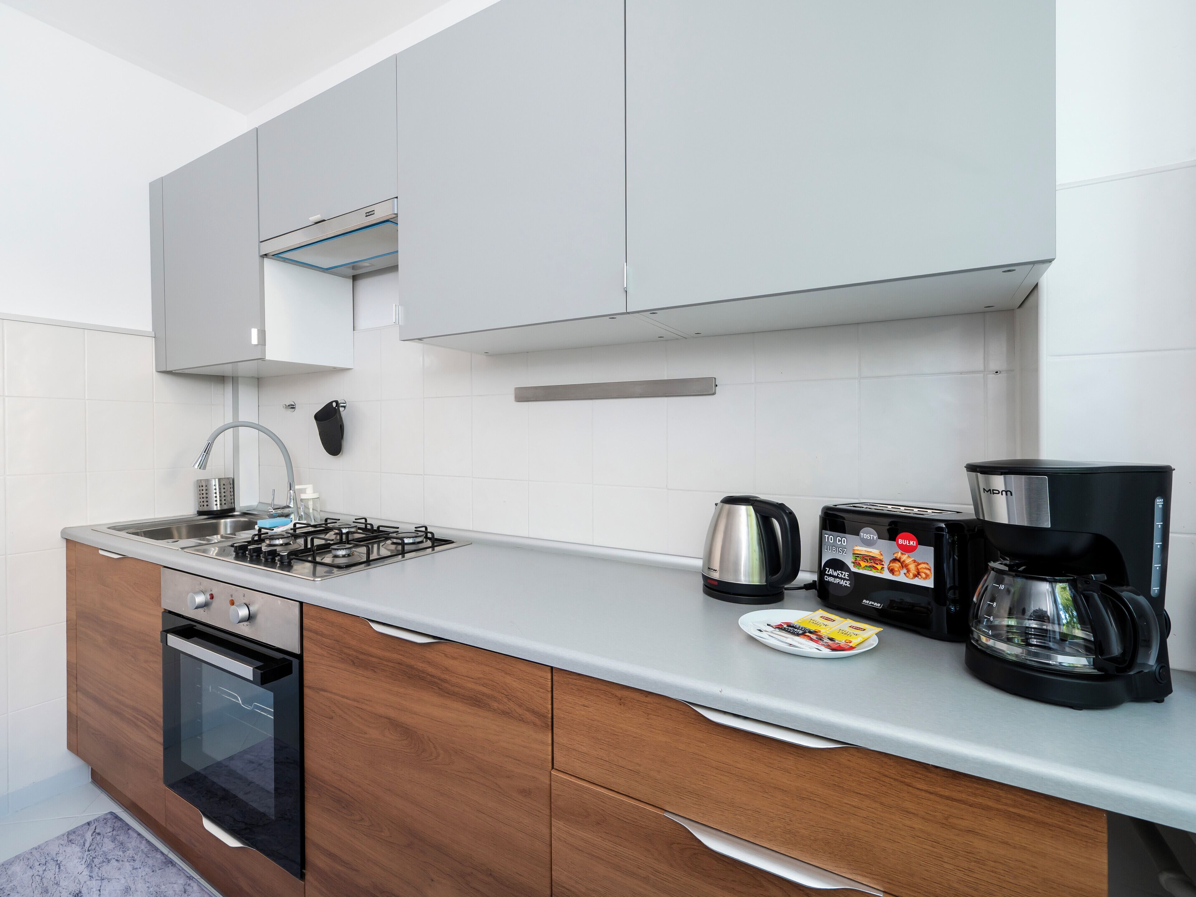Una cocina moderna con estufa a gas, horno, cafetera, hervidor y tostadora.