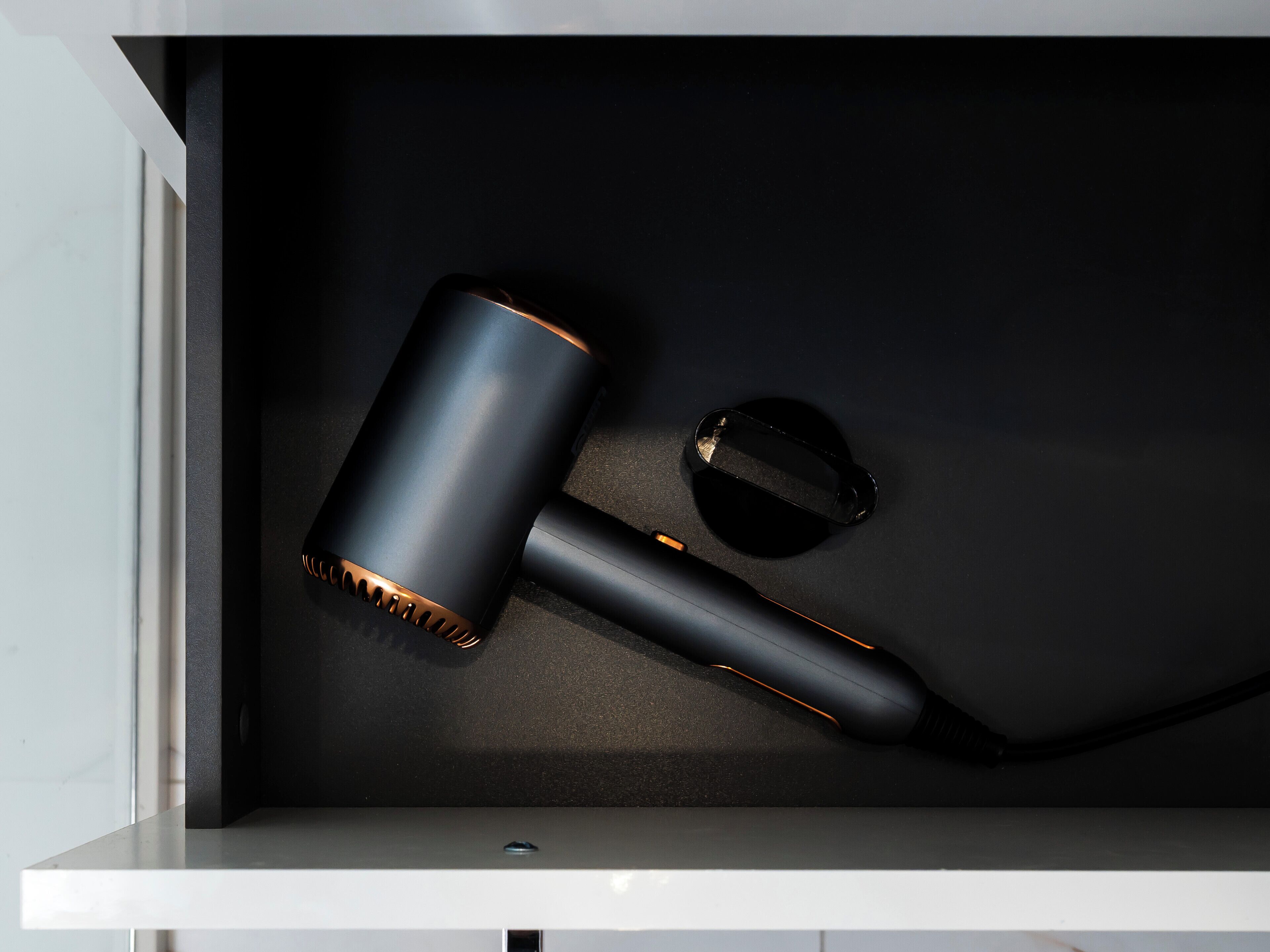 A drawer with a black cylindrical object, a smaller black object, and a black circular object.