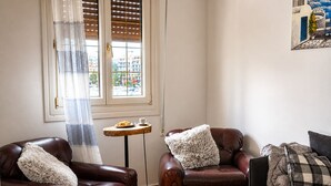 A living room with two brown leather sofas, a wooden coffee table, and a small round table with a plate of food and a cup. - Your Stunning 2Bdrm, 2BA with Seaview in Pireaus (Pireas)