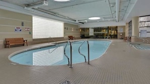 An indoor swimming pool with a tiled floor, a bench, and a window with blinds. - Breathtaking 20th Floor Skyline Views in the Heart of Downtown Calgary (Calgary)