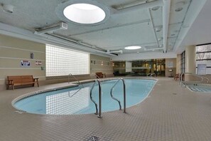 An indoor swimming pool with a tiled floor, a bench, and a window with blinds. - Breathtaking 20th Floor Skyline Views in the Heart of Downtown Calgary (Calgary)