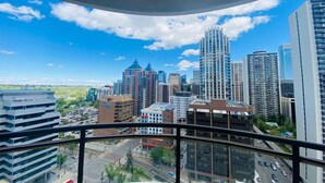 A cityscape with high-rise buildings, a clear sky, and a view from a balcony. - Breathtaking 20th Floor Skyline Views in the Heart of Downtown Calgary (Calgary)