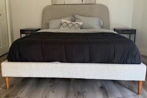 A bed with a black and white striped bedspread, two bedside tables, and a headboard. - Breathtaking 20th Floor Skyline Views in the Heart of Downtown Calgary (Calgary)
