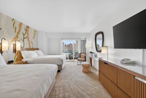 Ein Hotelzimmer mit zwei Betten, einem großen Fenster mit Stadtblick, einem Flachbildfernseher und einem Holztischchen.