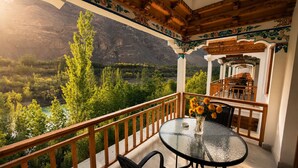 Un balcón con mesa y sillas, con vistas a un paisaje montañoso.