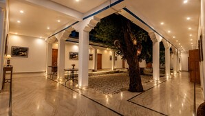 Un espacio interior amplio con un árbol, columnas blancas y suelo de mármol.
