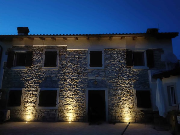 A stone building with multiple windows and doors, illuminated by ground lights. - Holiday home with air conditioning and terrace (Galižana)