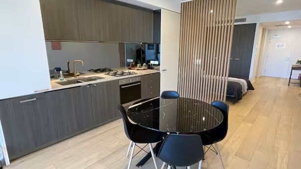 Een moderne keuken met een ronde eettafel en stoelen, een ingebouwde kookplaat en een groot raam.