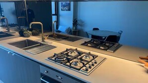 Een moderne keuken met een gasfornuis, spoelbak en oven.