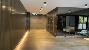 Een moderne lobby met een lange gang, kluisjes, een zithoek en een glazen scheidingswand.