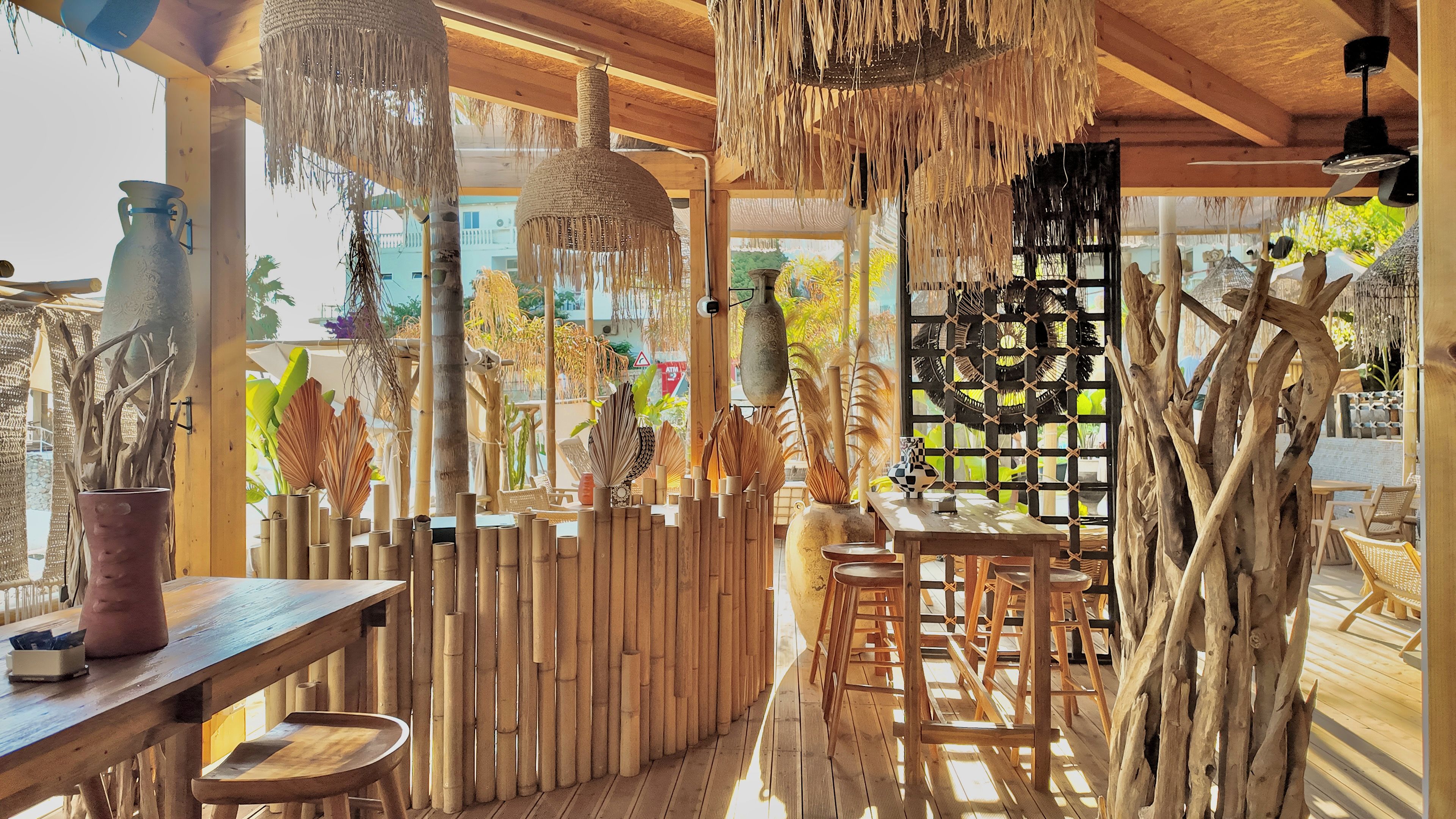 Eine Holzterrasse mit Bambusmöbeln und hängenden Dekorationen.