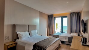 A hotel room with a bed, a desk, a chair, a TV, and a view of the sea. - Hotel Platinium Dhermi (Dhermi)