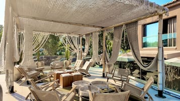 Un espacio de estar al aire libre cubierto con mobiliario de mimbre y una piscina al fondo.