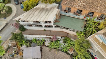 Un edificio de varios pisos con terraza en la azotea, piscina y jardín con diferentes plantas.
