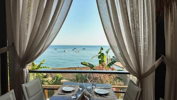 A table set for dining with a view of the sea and boats.