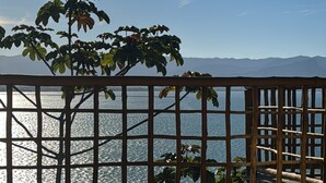 A wooden deck with a view of the sea and mountains.