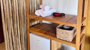 A wooden shelf unit with a white refrigerator, a woven basket, and a hairdryer.