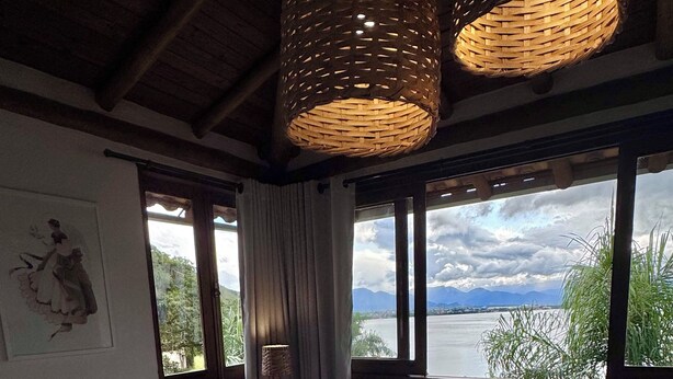 A bedroom with a large bed, a view of a body of water, and a mountain in the distance.