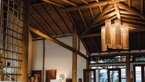 A spacious room with a high wooden ceiling, a sofa set, a coffee table, and large woven stools.