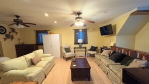 Un salon comprenant un canapé, des fauteuils, une table basse, un téléviseur et des ventilateurs de plafond.
