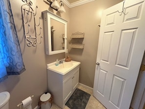 Un baño con inodoro, lavabo, espejo, toallero y una puerta.