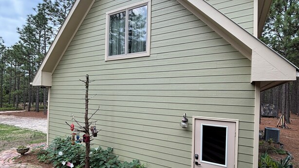 Une maison de plain-pied avec un toit en pente, une porte d’entrée et une fenêtre.