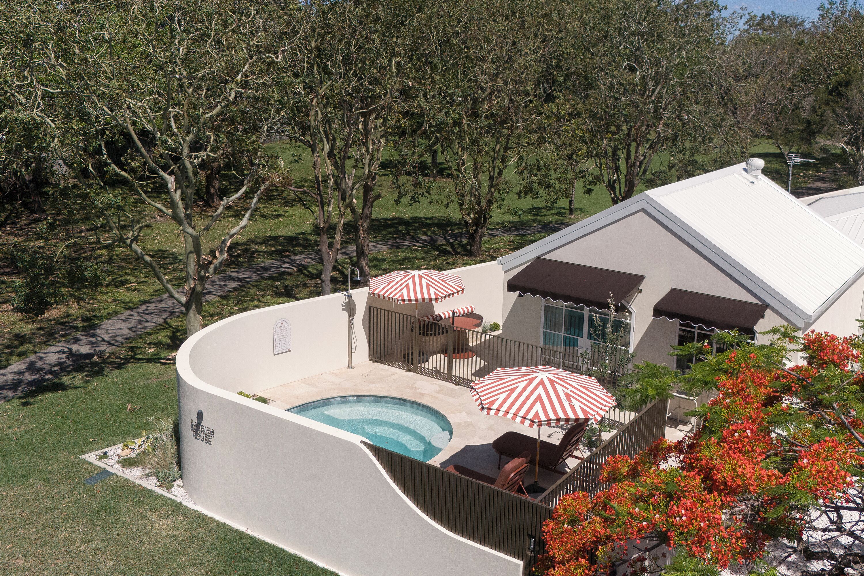 Une maison moderne dotée d’une piscine, d’un espace extérieur aménagé pour se détendre et d’une terrasse clôturée.