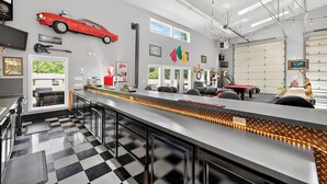 Una cocina moderna con piso a cuadros, una barra larga y un modelo de coche rojo en la pared.