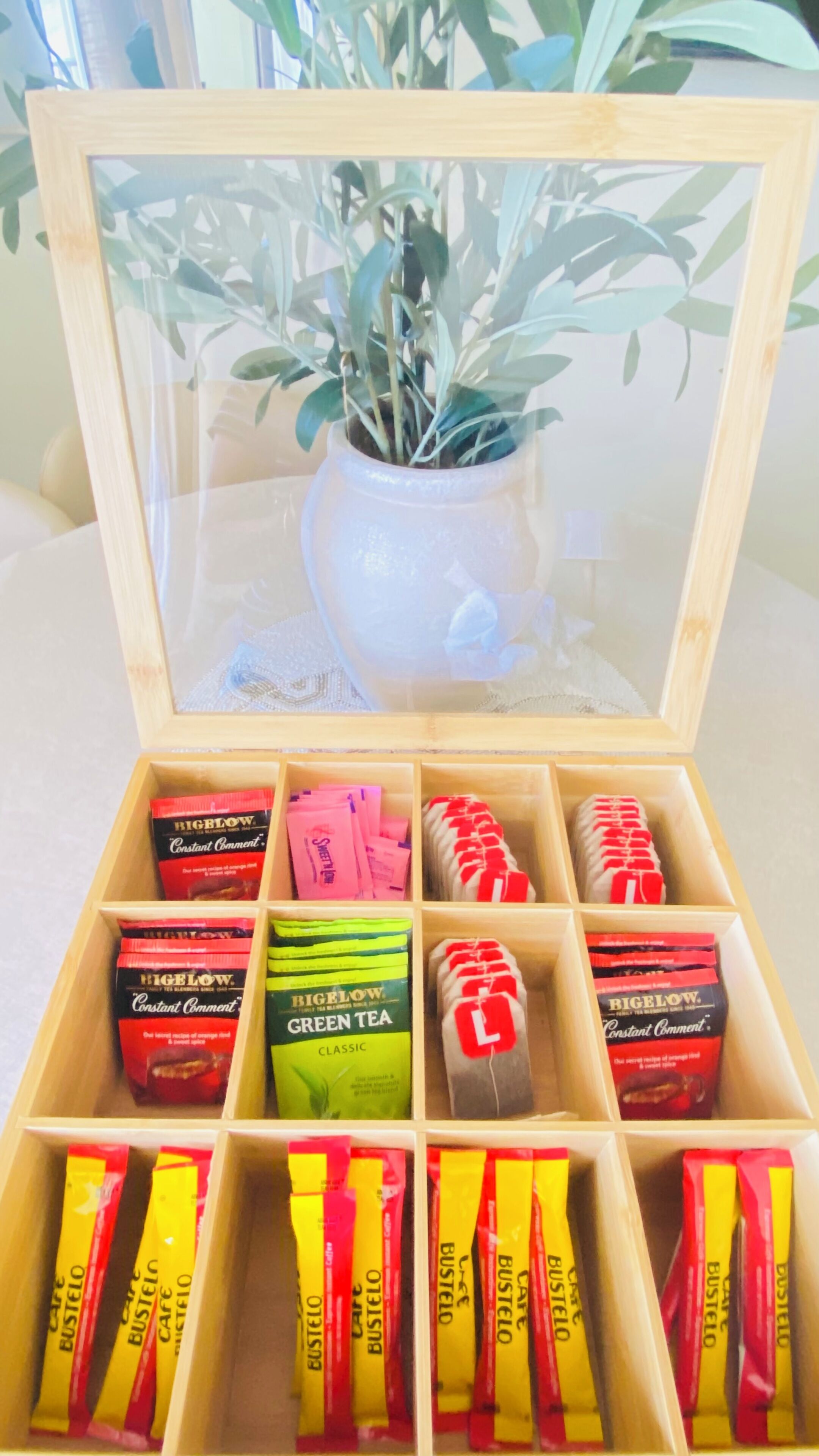 A wooden box with compartments containing various tea bags and a potted plant.