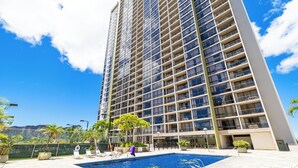 A high-rise hotel with a swimming pool, outdoor seating, and a view of the mountains. - Waikiki Cozy &Natural OceanMountain view hotel suite Free-parking  (Honolulu)