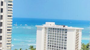 A high-rise hotel with multiple balconies, overlooking a beach with boats and clear blue waters. - Waikiki Cozy &Natural OceanMountain view hotel suite Free-parking  (Honolulu)