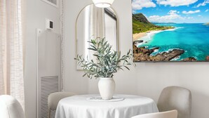 A room with a round table, a potted plant, a chair, and a wall-mounted mirror. - Waikiki Cozy &Natural OceanMountain view hotel suite Free-parking  (Honolulu)