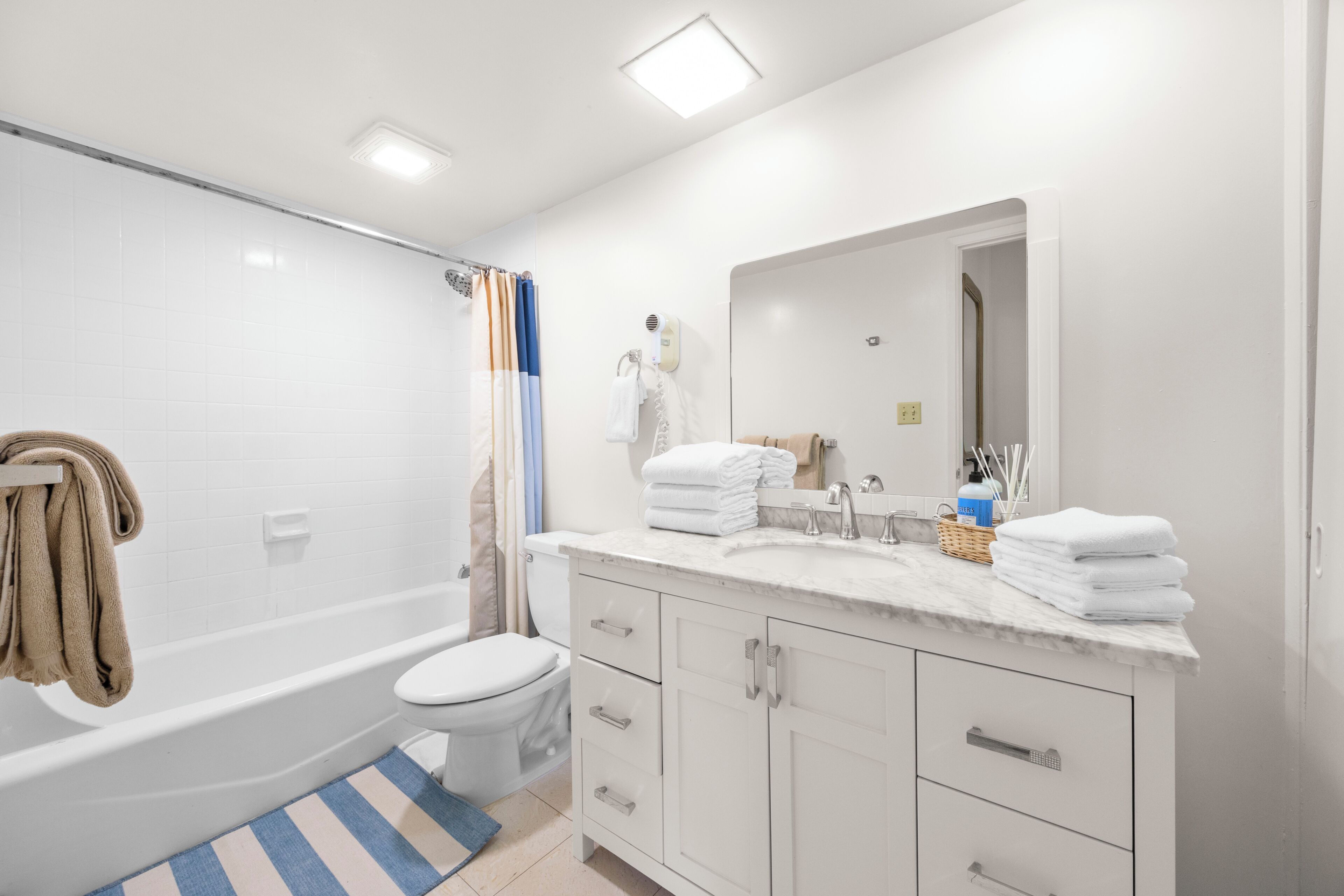 Une salle de bain moderne équipée d’une baignoire, de toilettes, d’un meuble-lavabo et d’un miroir.