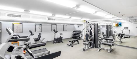 A gym with treadmills, elliptical machines, weight benches, and free weights.