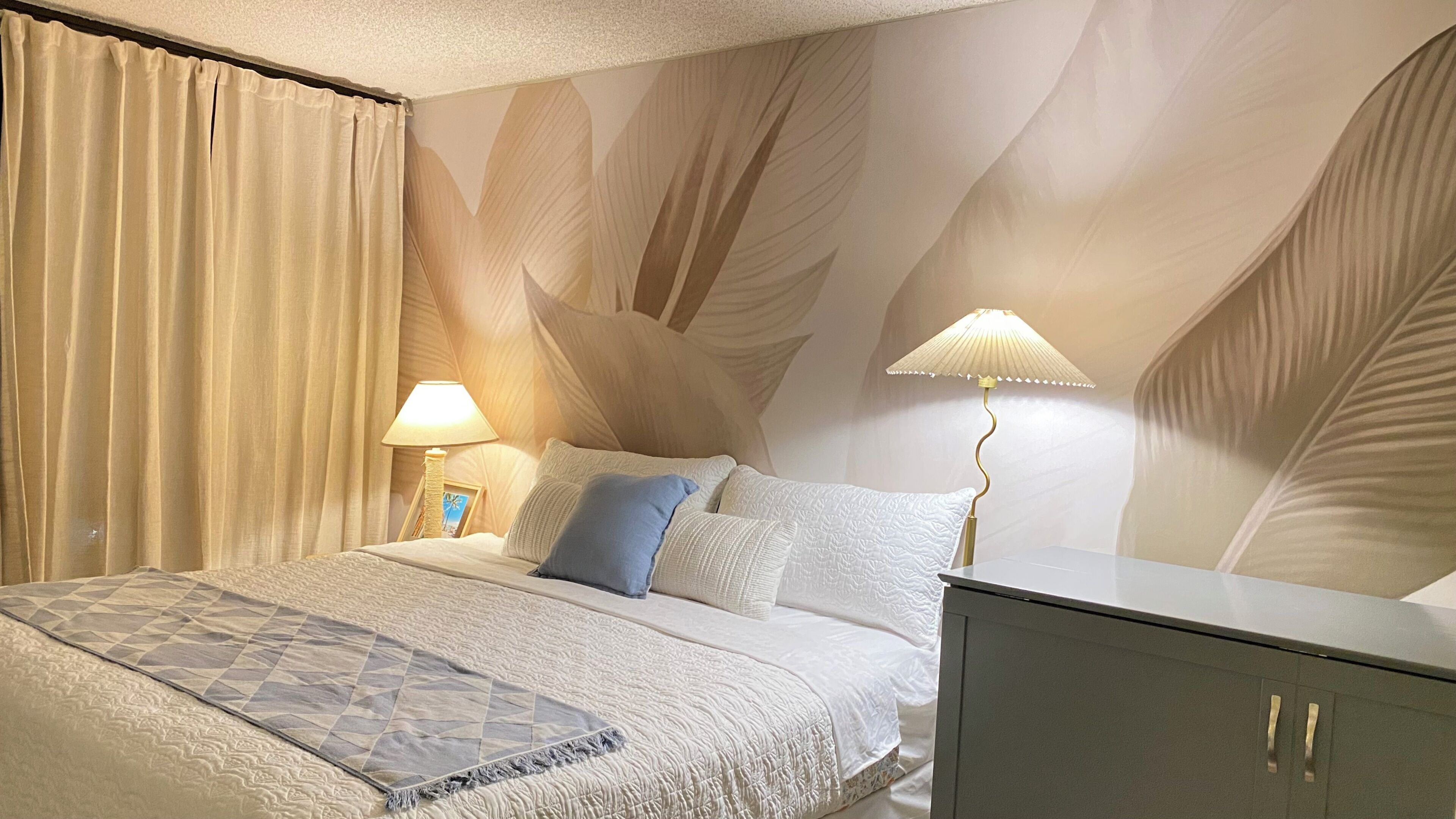 Un dormitorio con cama, almohadas, mesita de noche, lámpara y armario.