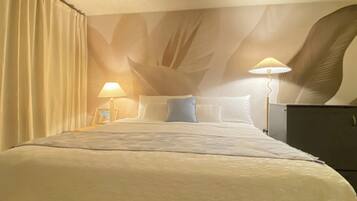 A hotel room with a bed, two bedside lamps, a nightstand, and a large wall mural.