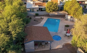 Ein Garten mit Swimmingpool, Gartenmöbeln und einer überdachten Sitzgelegenheit.