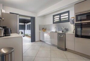 Eine moderne Küche mit Geschirrspüler, Backofen und einem Fenster mit Jalousien.
