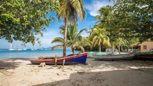 A beach with boats, palm trees, and a clear sky. - 2BR Apartment Planteur - Beachfront (Les Trois-Îlets)