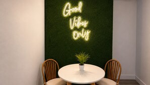 A room with a neon sign reading 'Good Vibes Only' on a green wall, two wooden chairs, a small table with a plant, and a white ceiling light. -  Cozy coastal stay in Fort Lauderdale near las olas,Wilton manors,airport,Port (Fort Lauderdale)