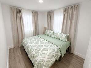 Ein Schlafzimmer mit Bett, Vorhängen und einem Kopfteil.