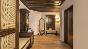 A hallway with wooden flooring, a mirror, a bench, and a lamp.