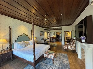 A four-poster bed with a nightstand, a small table with a lamp, a chair, and a fireplace. - Brij Anayra Dharamshala (Dharamshala)
