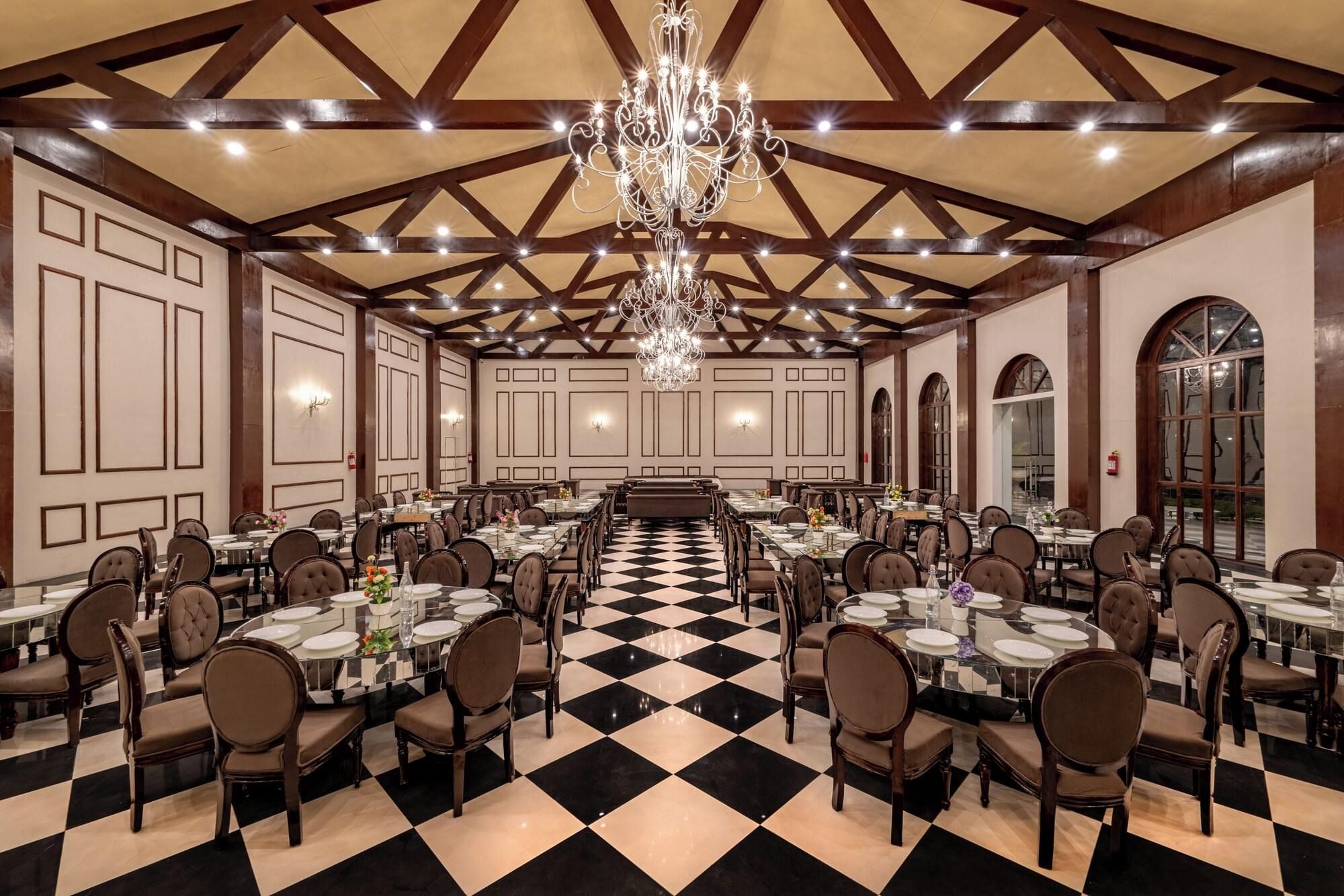 A large banquet hall with high ceilings, chandeliers, and a checkered floor.
