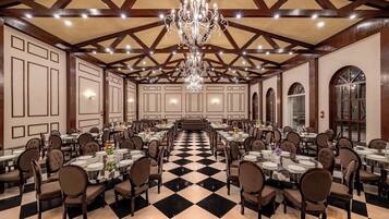 A large banquet hall with high ceilings, chandeliers, and a checkered floor.