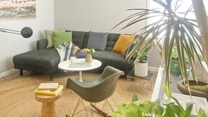 Un saló modern amb un sofà, una taula de centre, una cadira bressol i diverses plantes.