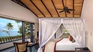 A bedroom with a bed, a chair, a small table, a ceiling fan, and a view of the ocean. - Niraamaya Retreats Backwaters and Beyond, Kumarakom (Kottayam)