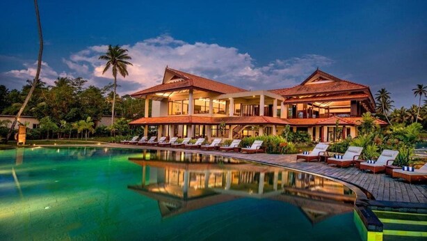 A resort with a swimming pool, lounge chairs, and a large building with a red roof. - Niraamaya Retreats Backwaters and Beyond, Kumarakom (Kottayam)